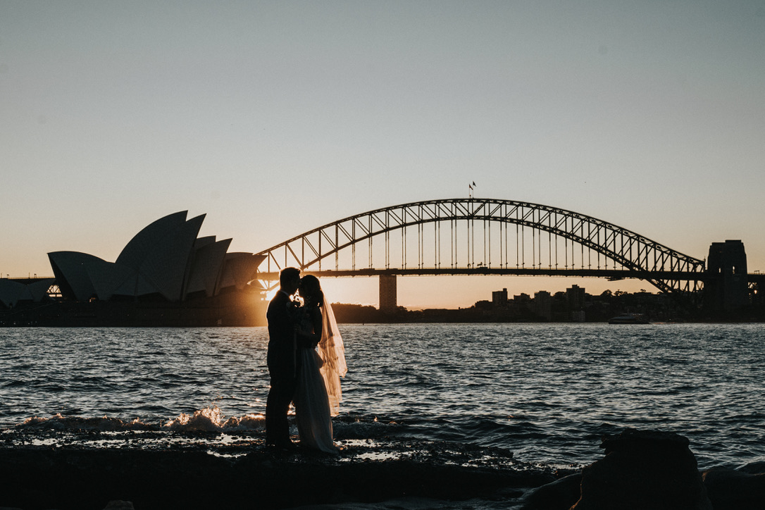 Couple silhouetted against the Opera House and Harbour Bridge at sunset