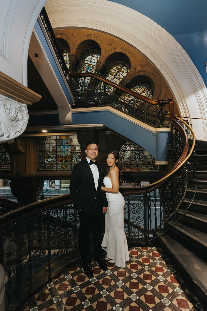 Couple on a grand heritage staircase with stained glass
