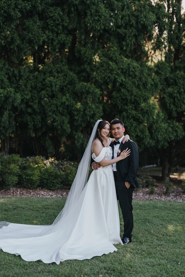 Couple embracing in a garden with a long cathedral veil