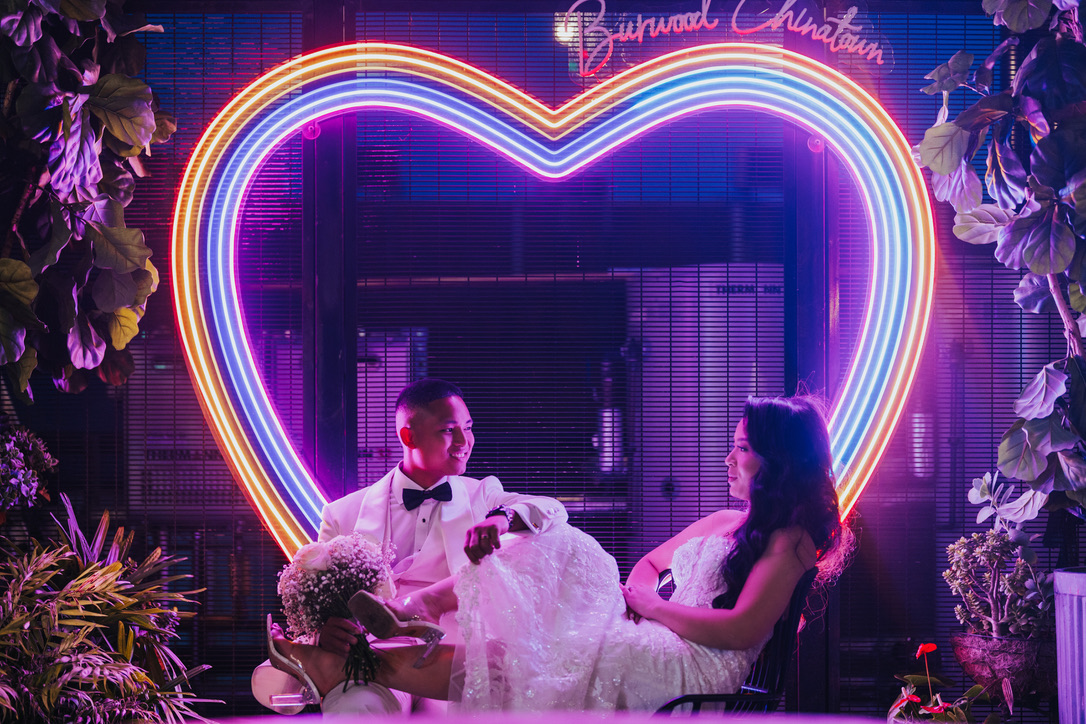 Couple relaxing beneath a glowing neon heart at night