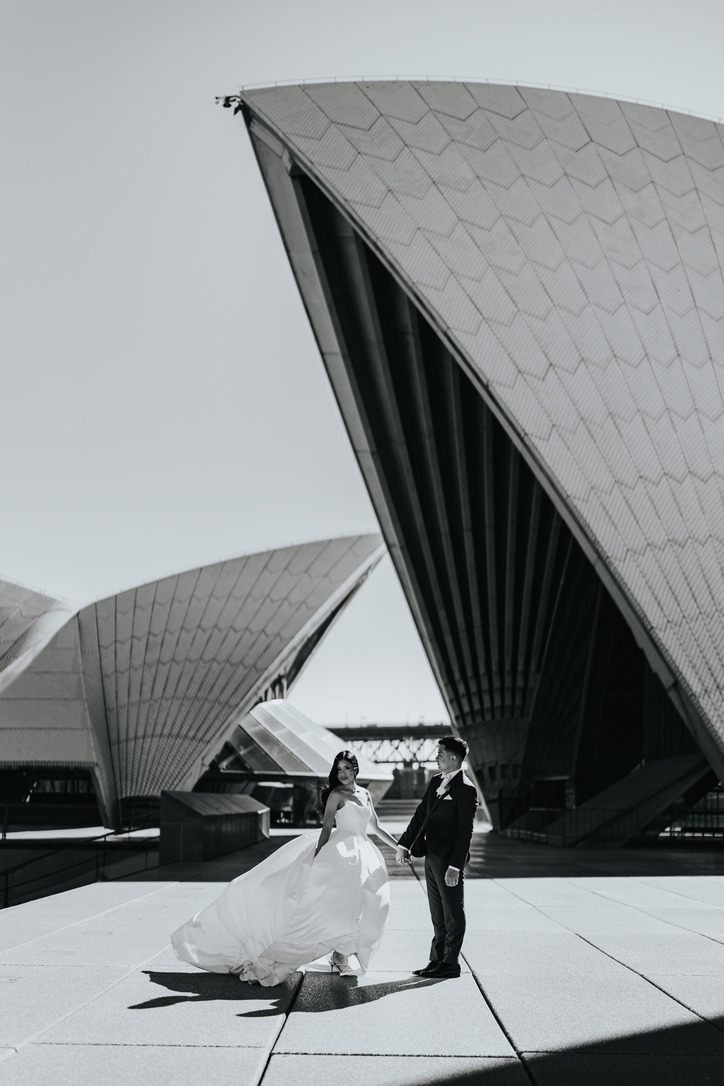 Black and white portrait of the couple beneath the Opera House sails