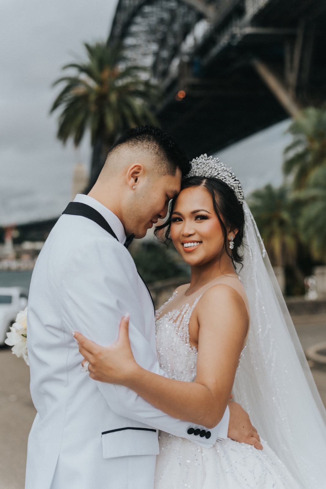Groom in a white tuxedo holding the bride close
